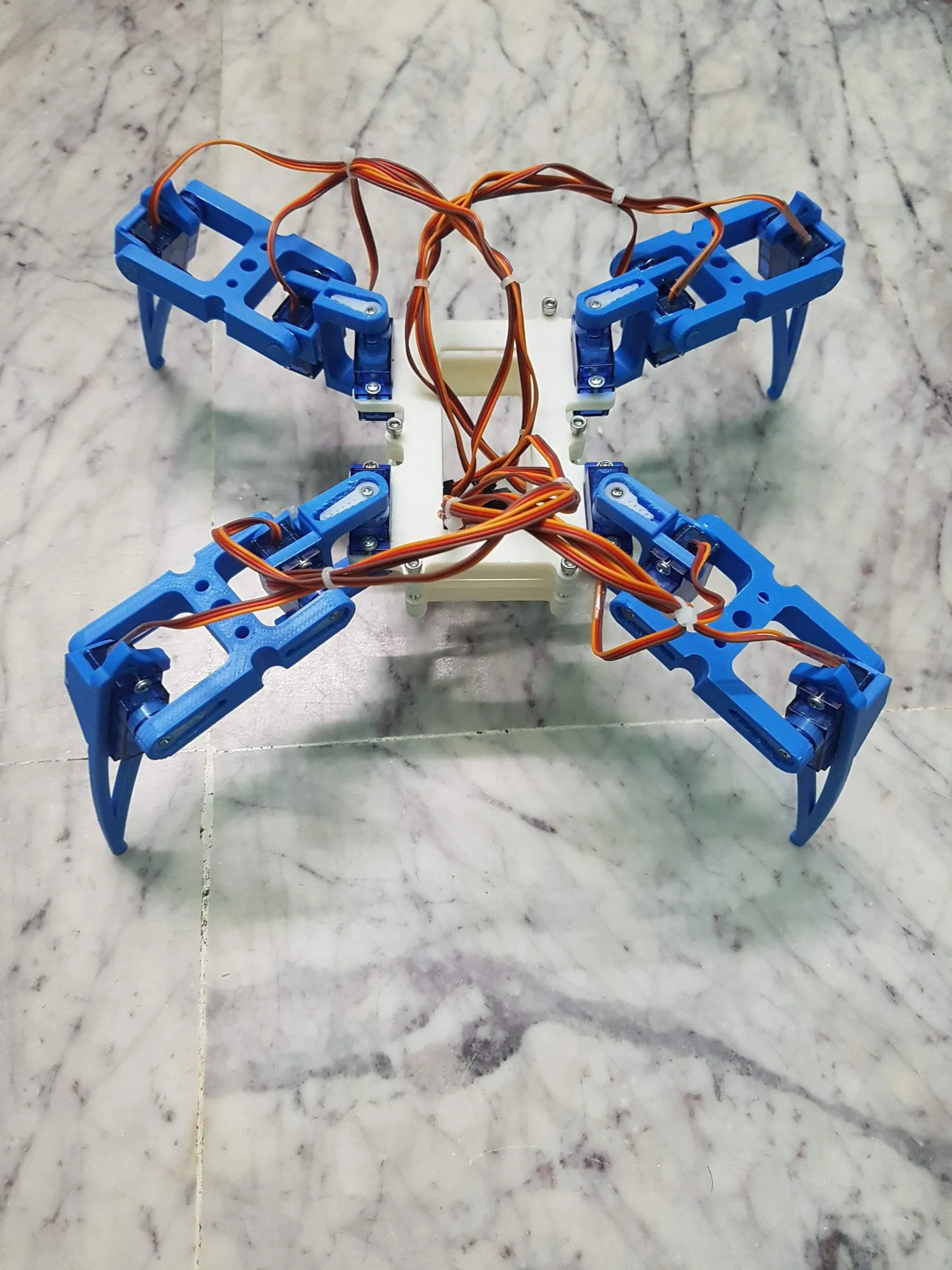 A four-legged walking robot with blue 3D-printed legs and servo motors