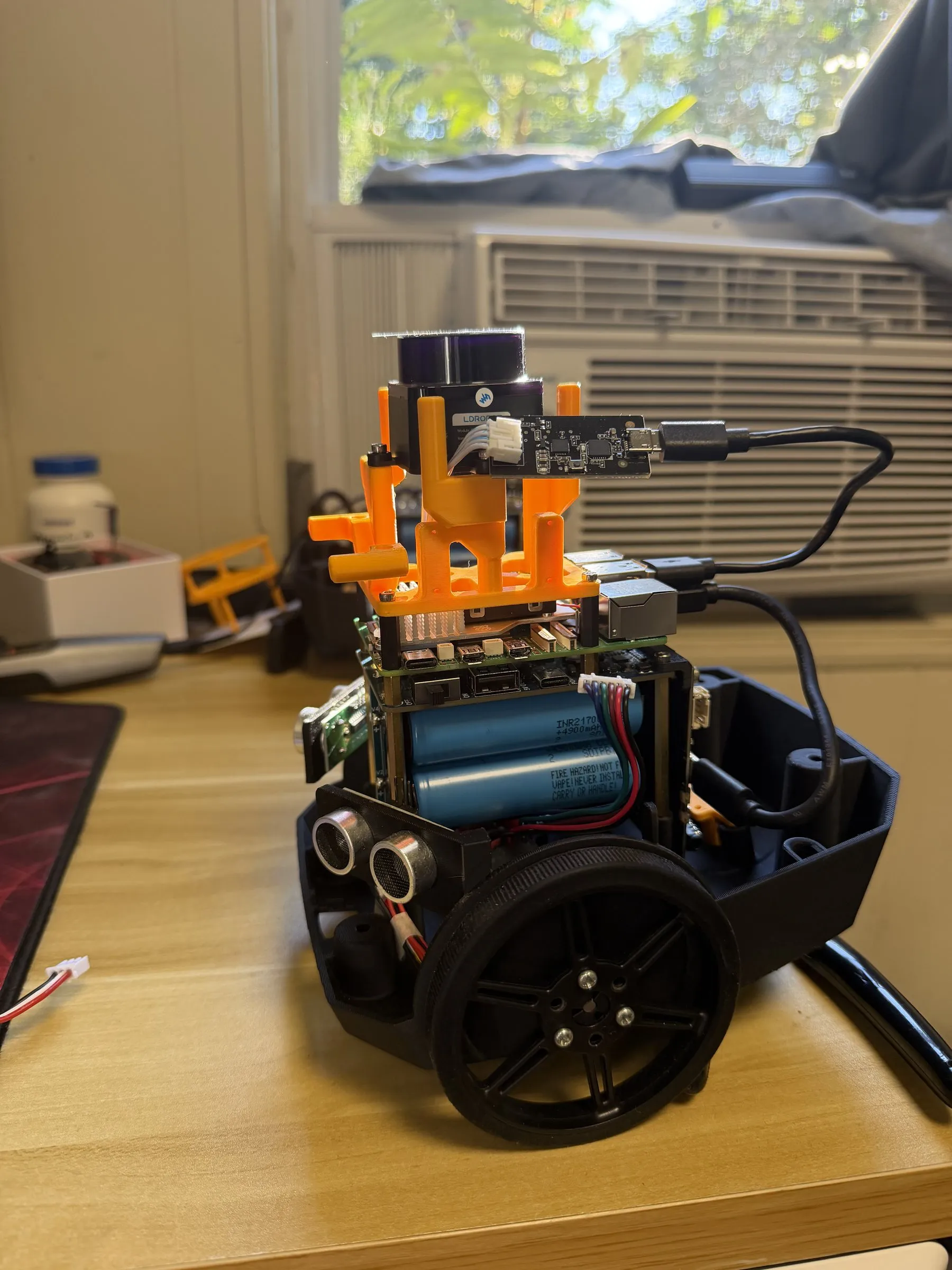 Robot chassis with wheels, battery pack, sensors and an orange 3D-printed mount