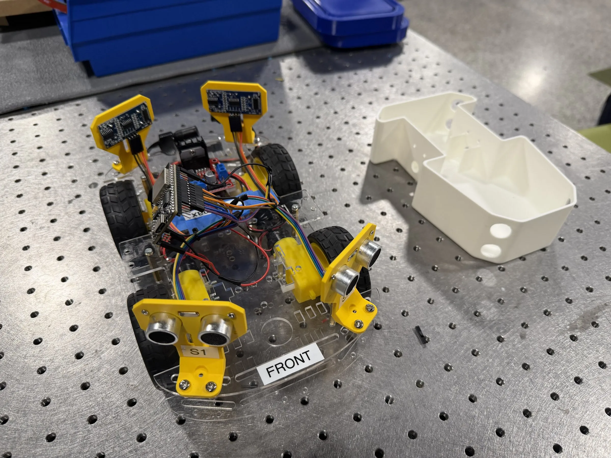 An early clear acrylic chassis with yellow gear motors next to the first white shell