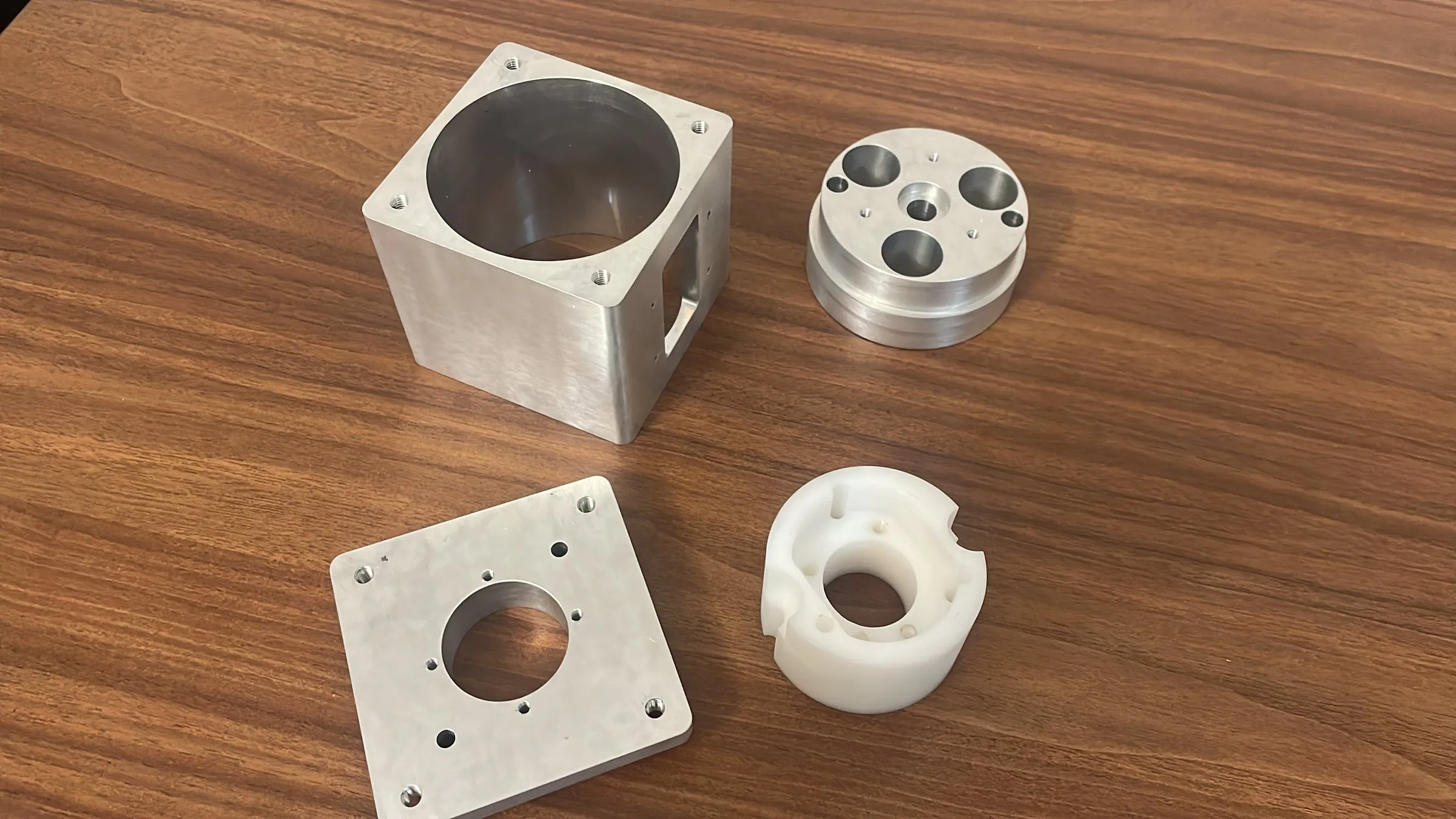 Machined aluminum motor-mount parts and a white Delrin block