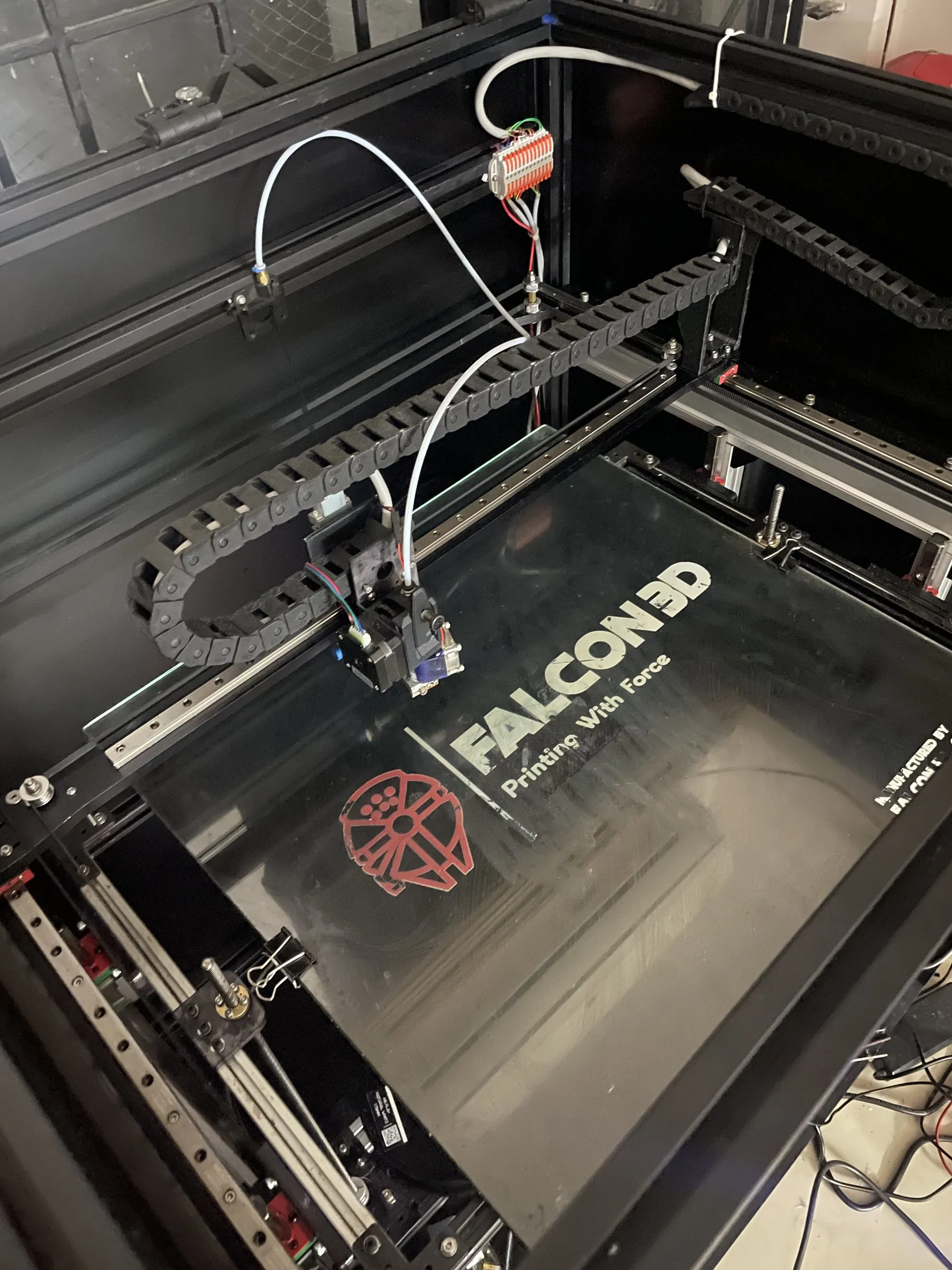 Printer interior with the Falcon 3D logo on the bed and a cable chain